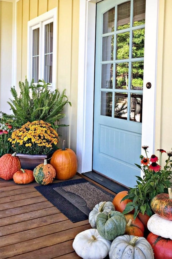 front porch with yellow flowers and pumpkins