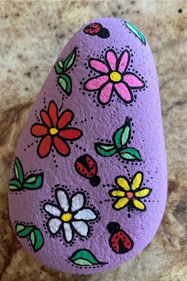 puple painted pebble with flower decoration