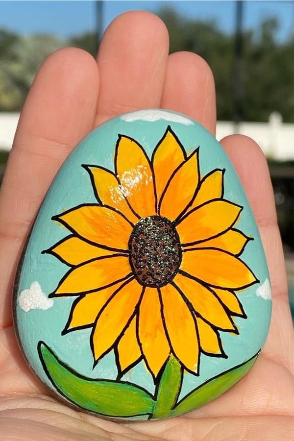 hand painting rock with yellow flower