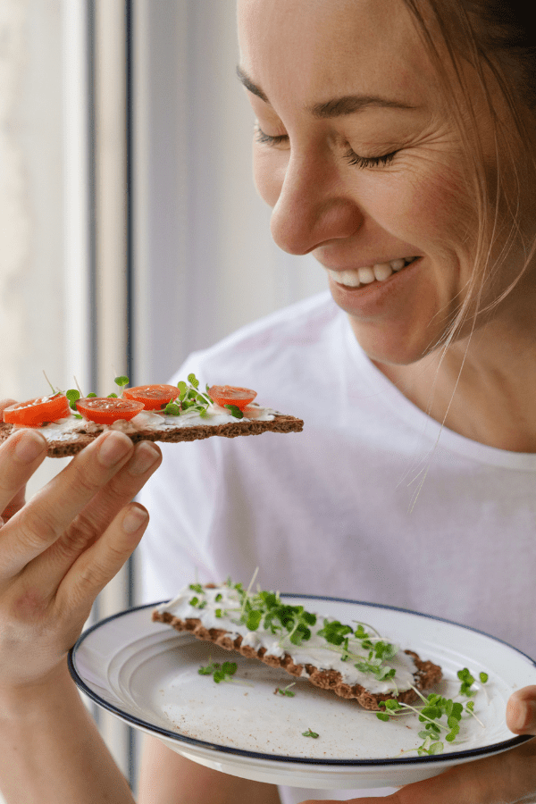 Smiling woman eating rye bread with microgreens