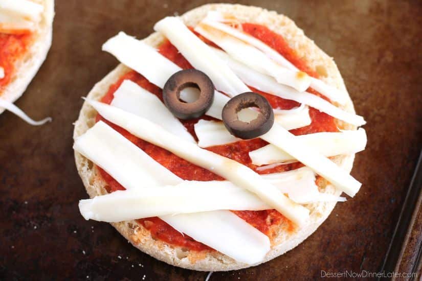 Mini pizzas topped with criss-crossed cheese bandages and olive eyes