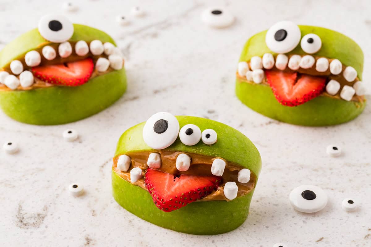 Apple wedge monsters with creamy filling, a fruit tongue and candy eyes