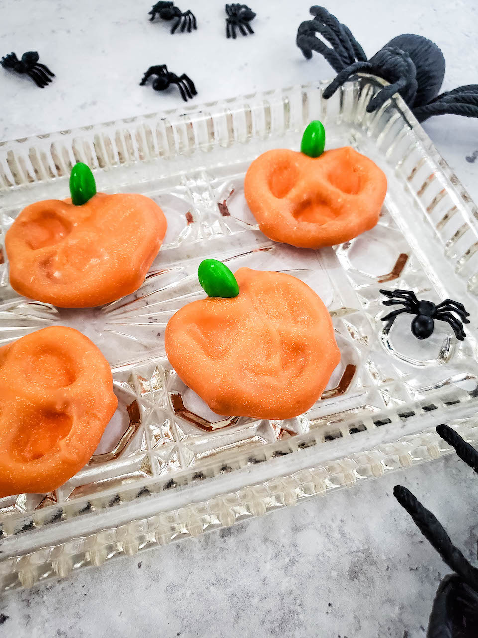 Orange candy-coated pretzels with green candy stems lined up as pumpkins