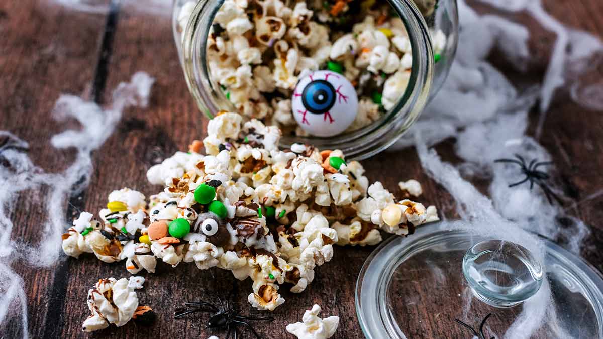 Bowl of Halloween popcorn mix tossed with colourful candies
