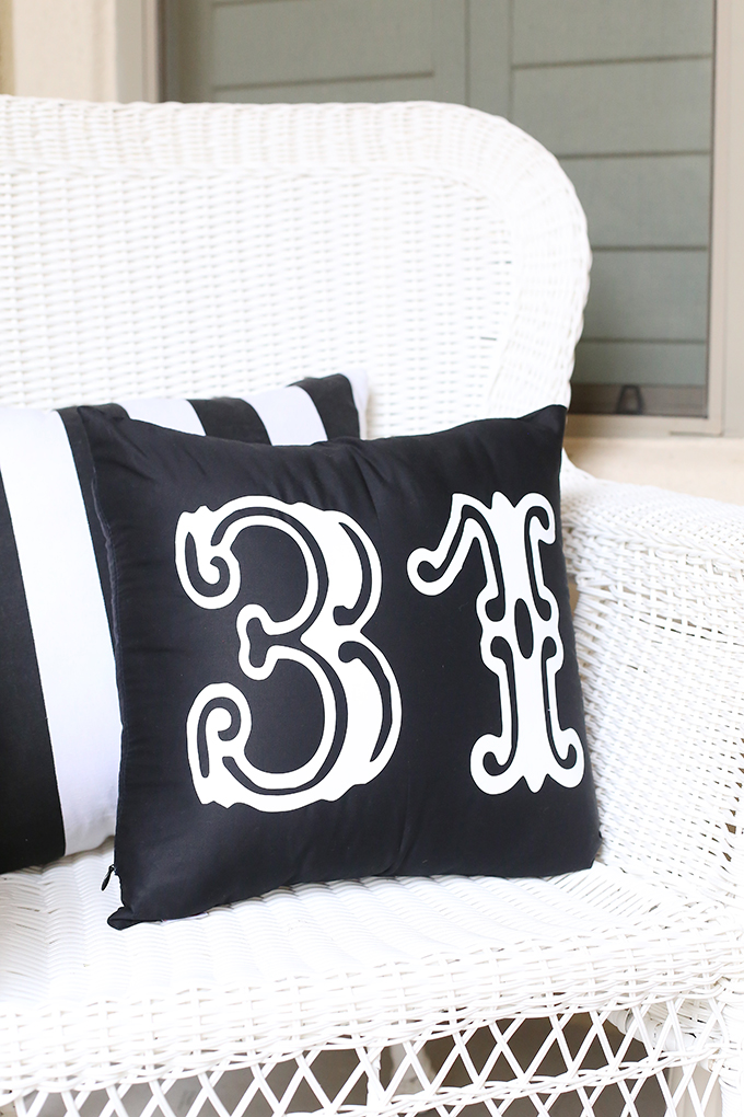Black pillow with white 31 lettering on a porch chair with black and white cushions