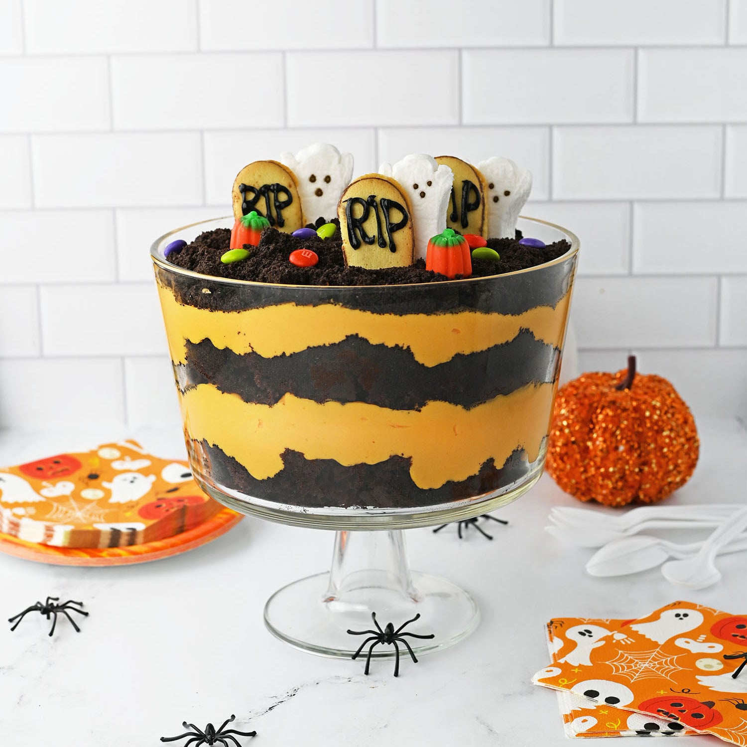 Halloween trifle layered in a glass bowl with ghost and tombstone toppers