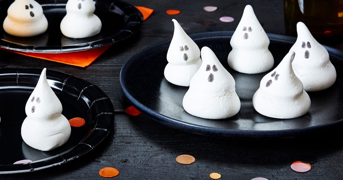 Standalone meringue ghosts with simple dark faces on a tray