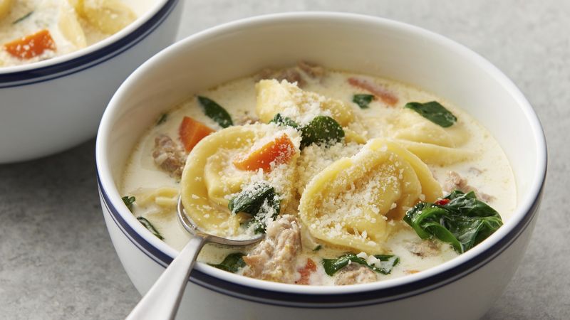 Creamy tortellini and sausage soup in a bowl with a spoon
