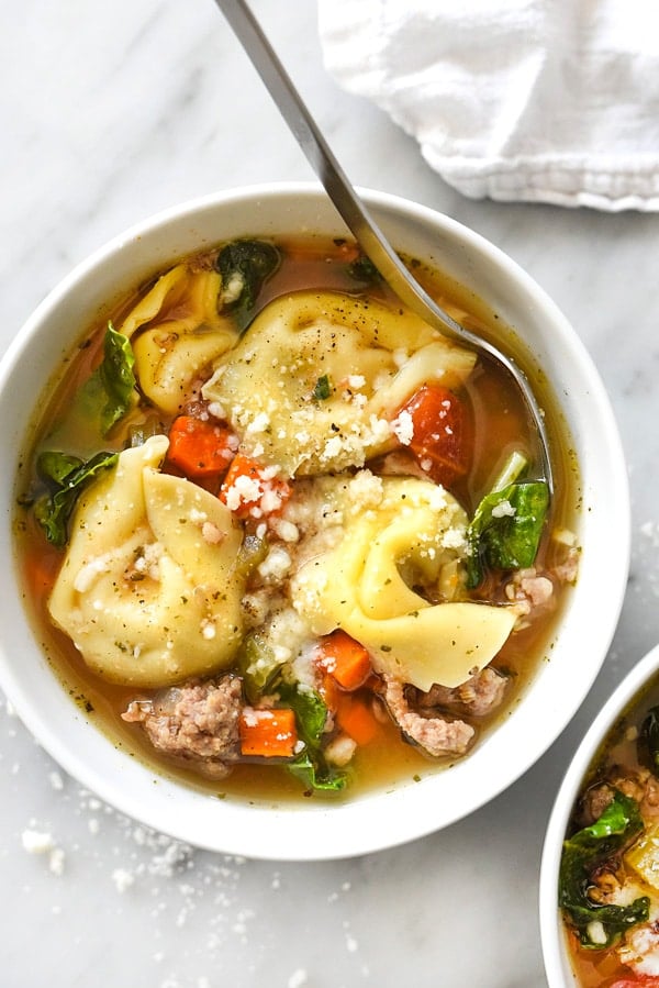 Tortellini soup with sausage and kale served in a bowl