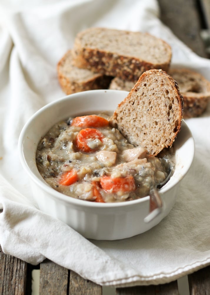 Chicken wild rice soup with carrot pieces and a slice of bread