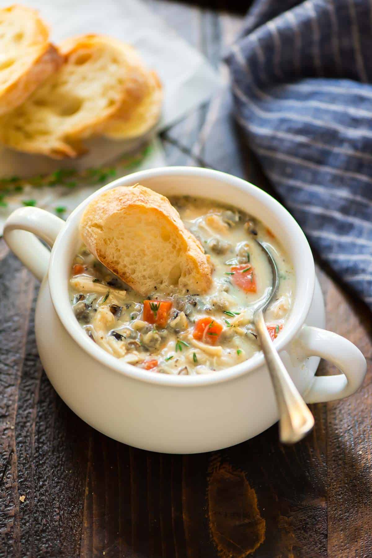 Creamy chicken and wild rice soup in a white handled bowl with bread